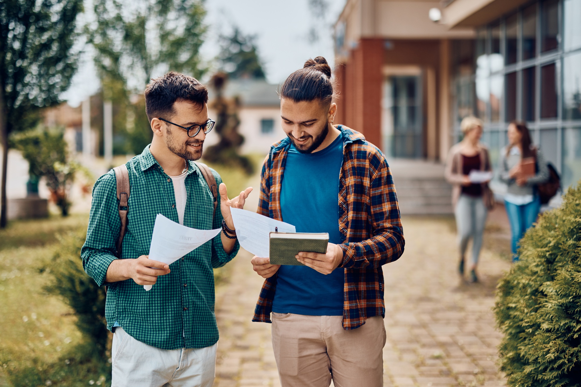 Happy colleges students analyzing their exam results at campus.