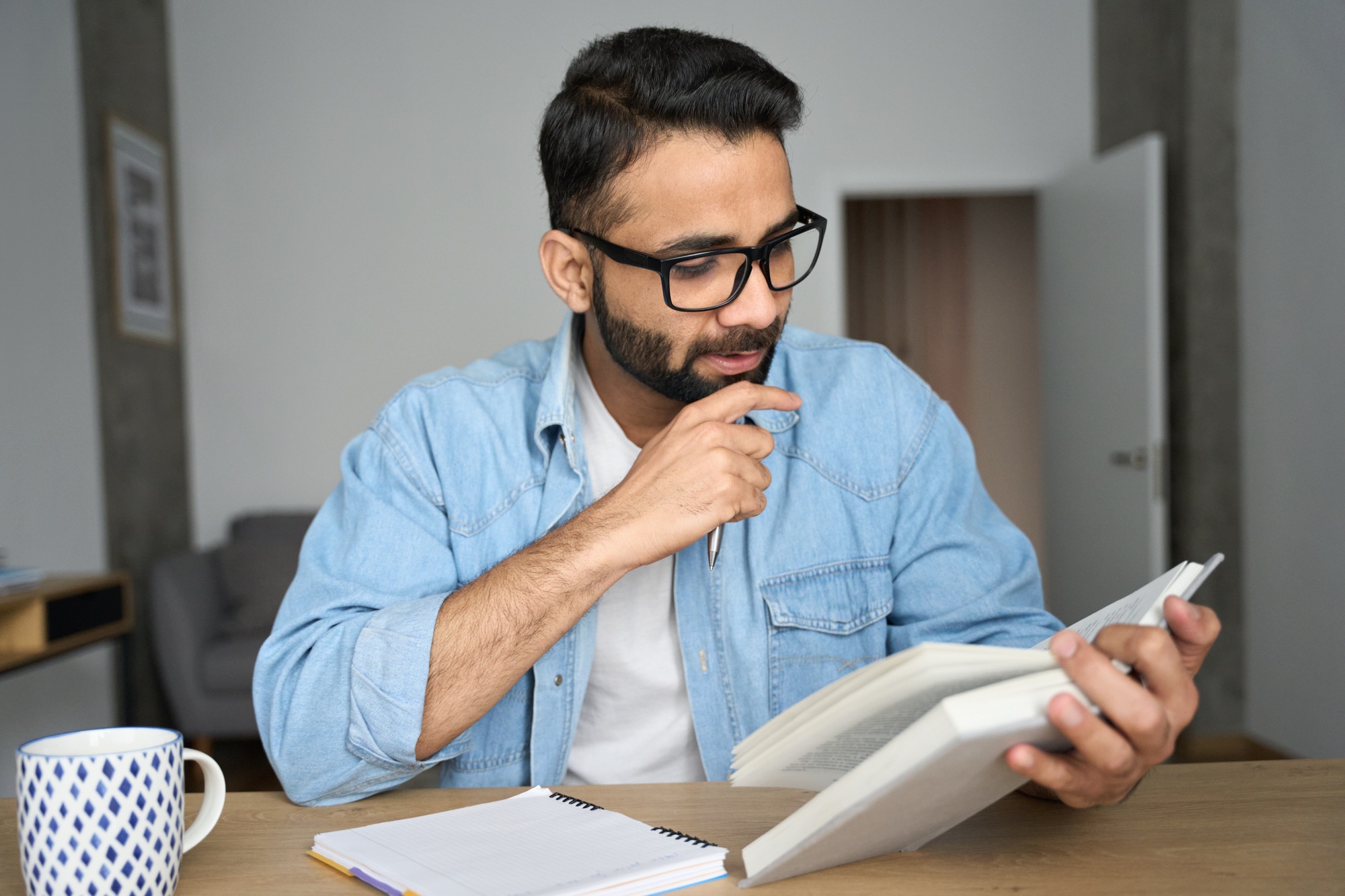 Indian eastern student reading book exam preparing at home workplace.
